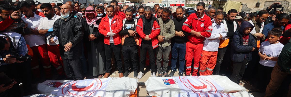 Members of the Palestine Red Crescent and other emergency services pray by the bodies of fellow rescuers killed a week earlier by Israeli forces