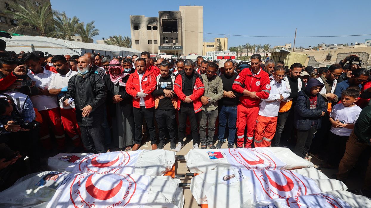 Members of the Palestine Red Crescent and other emergency services pray by the bodies of fellow rescuers killed a week earlier by Israeli forces