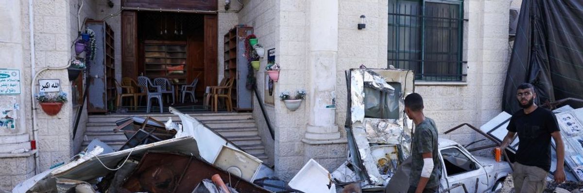 Men walk among rubble in front of a building in the occupied West Bank city of Jenin on July 4, 2023