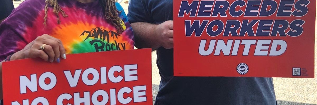 Mercedes-Benz employees hold up signs supporting the United Auto Workers