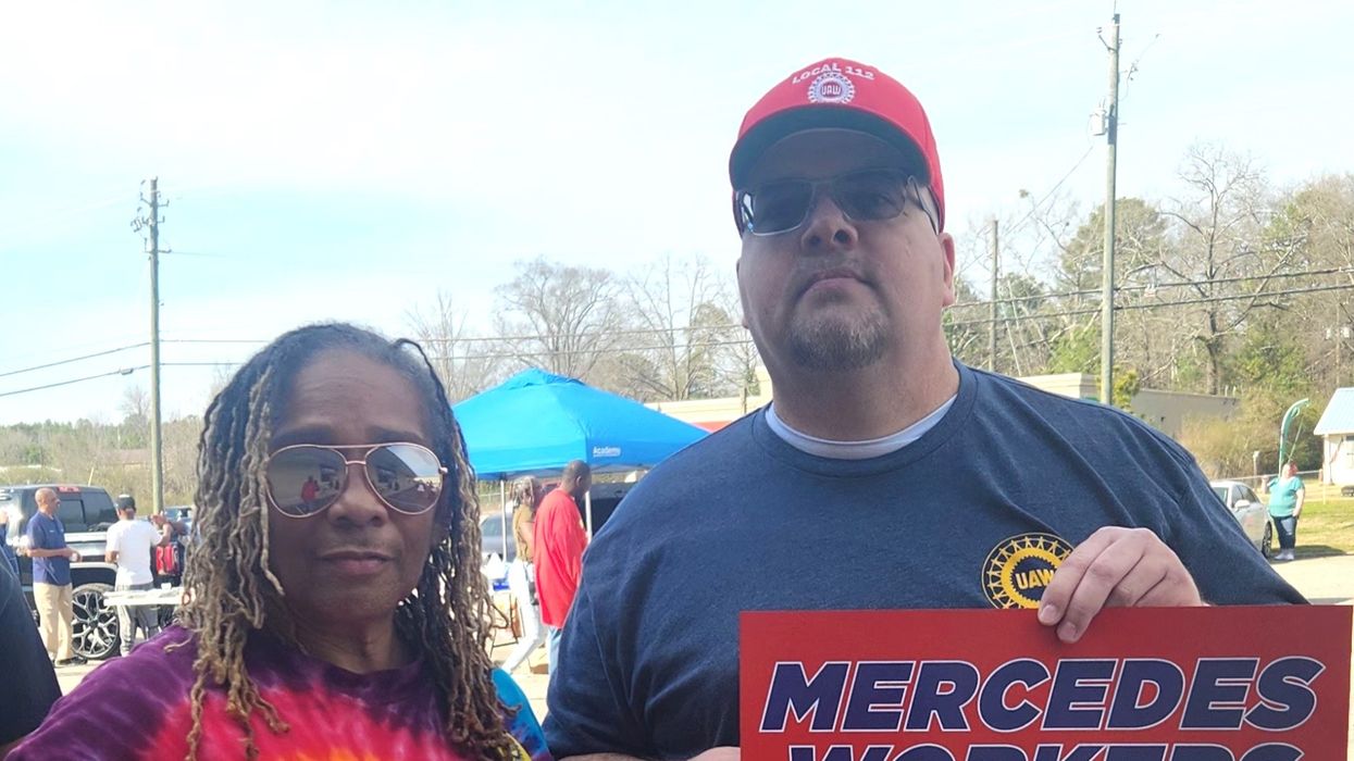 Mercedes-Benz employees hold up signs supporting the United Auto Workers