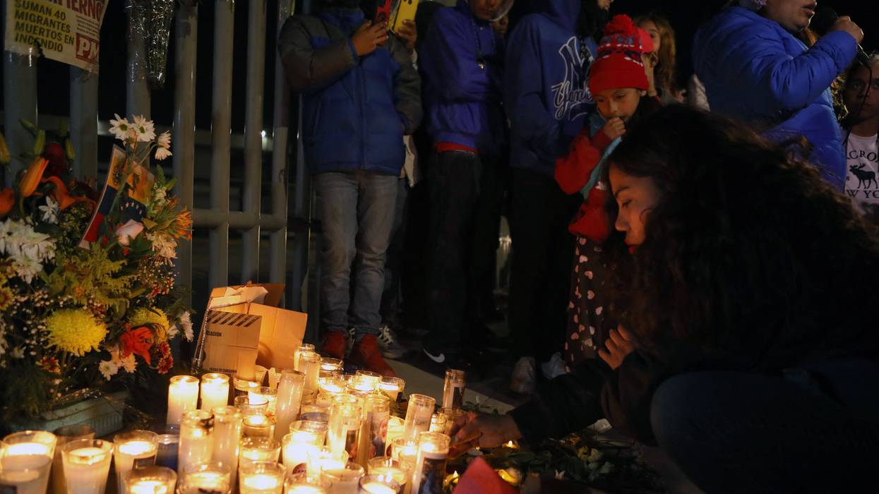 Migrants and activists light candles at a vigil