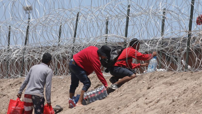 Migrants from Mexico try to get through barbed wire barriers along the Texas border to get to the U.S.