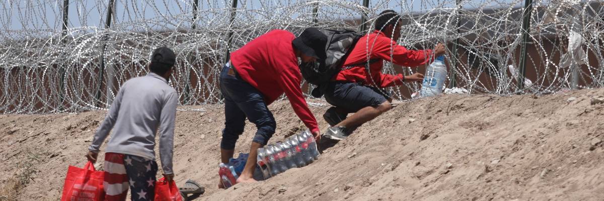 Migrants from Mexico try to get through barbed wire barriers along the Texas border to get to the U.S.