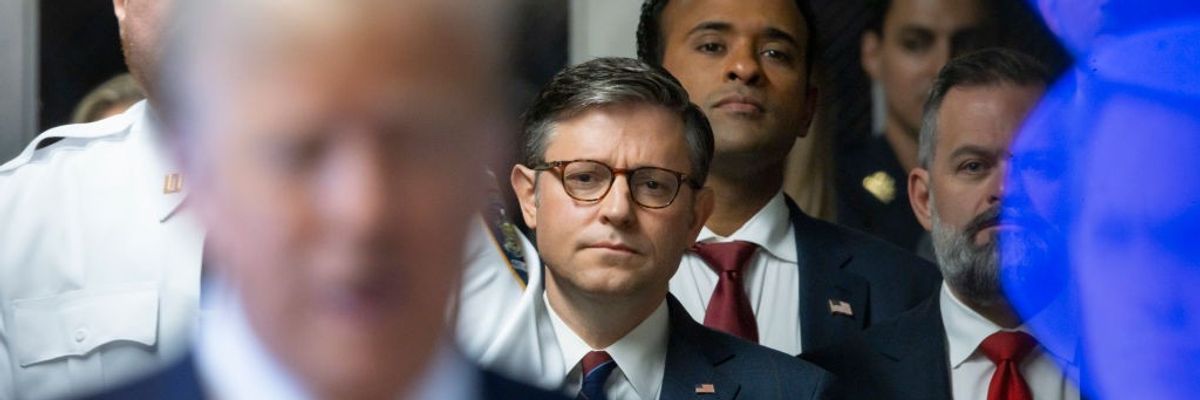 Mike Johnson watches as Donald Trump speaks