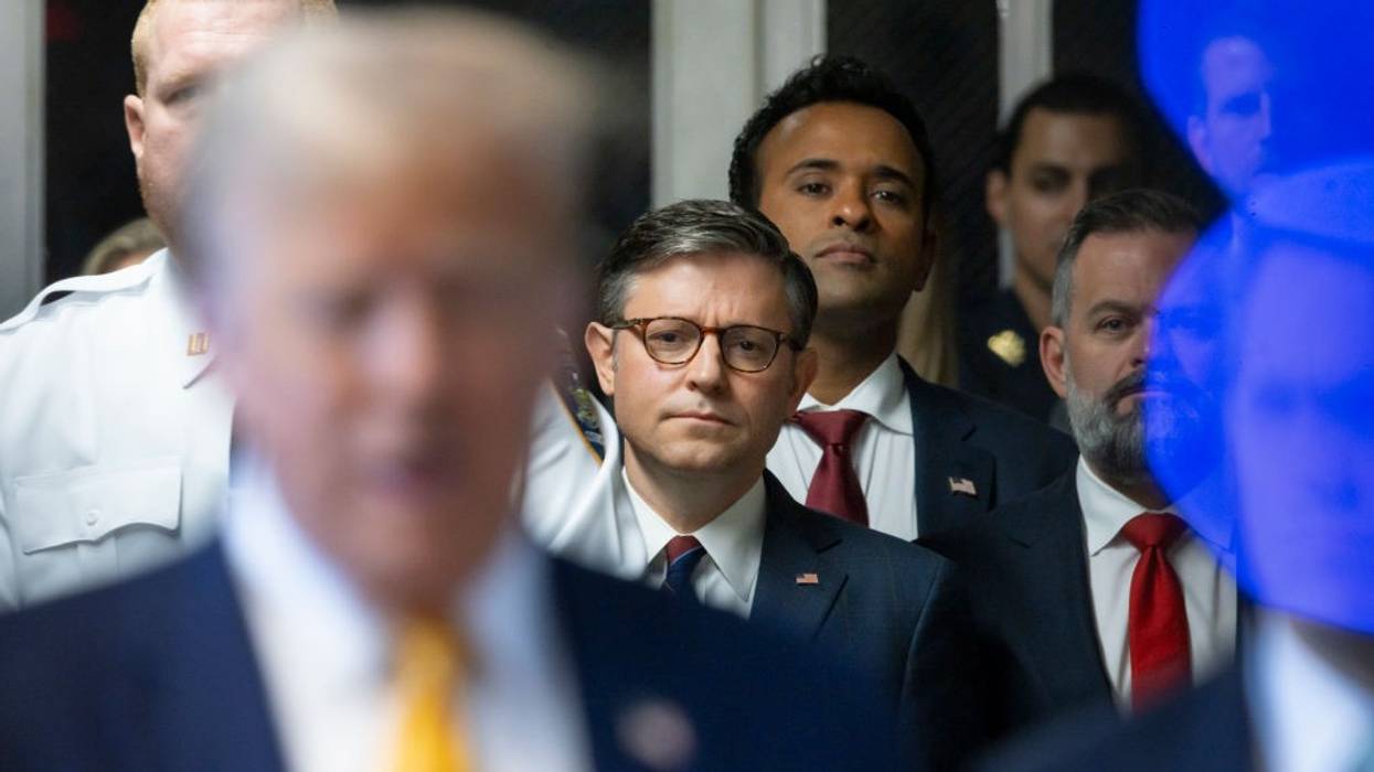 Mike Johnson watches as Donald Trump speaks