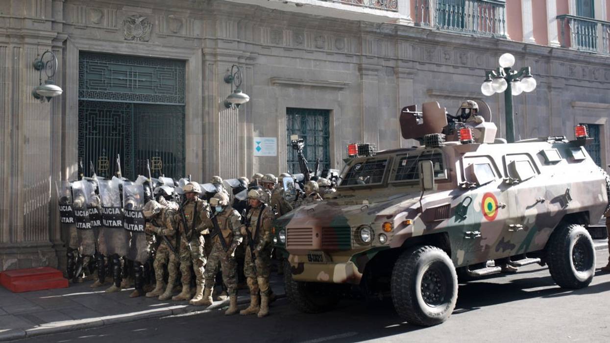 Military members stand guard with an armored truck