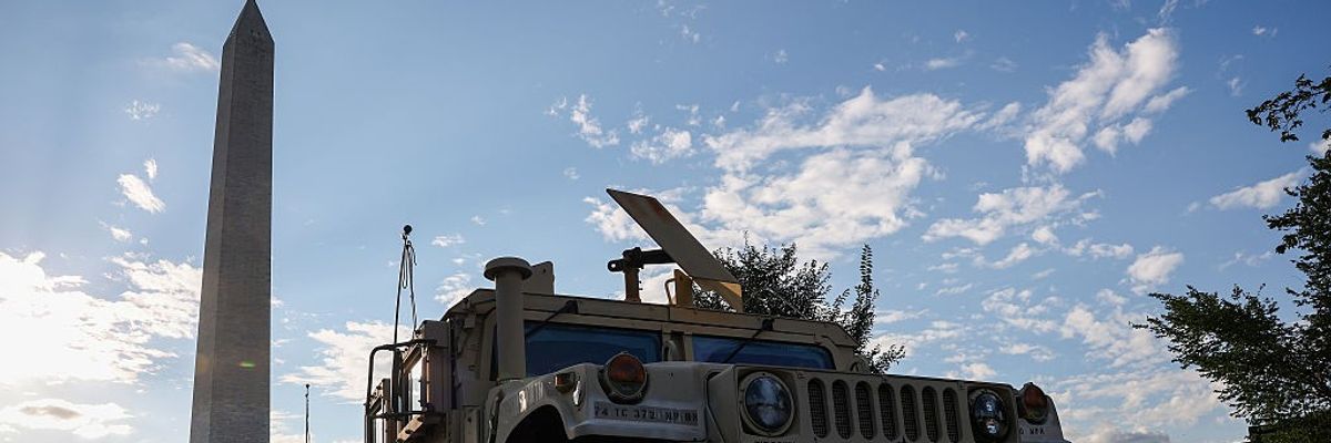 Military vehicle parks in front of Washington monument.