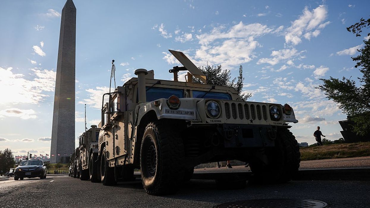 Military vehicle parks in front of Washington monument.