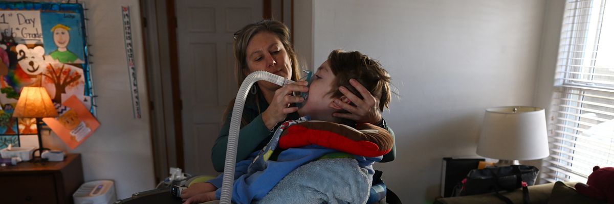 Mother helping her sick child with breathing machine