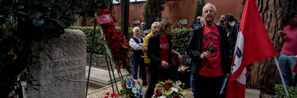 Mourners with a flag stand at the grave of Antonio Gramsci.