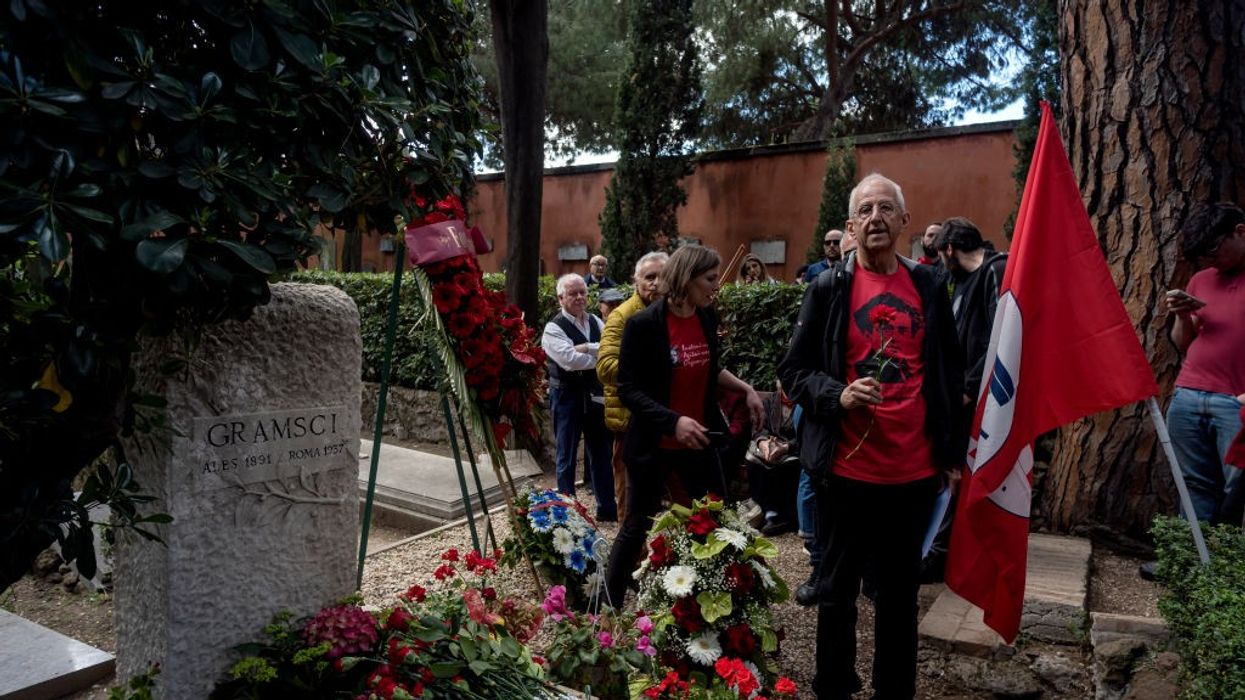 Mourners with a flag stand at the grave of Antonio Gramsci.