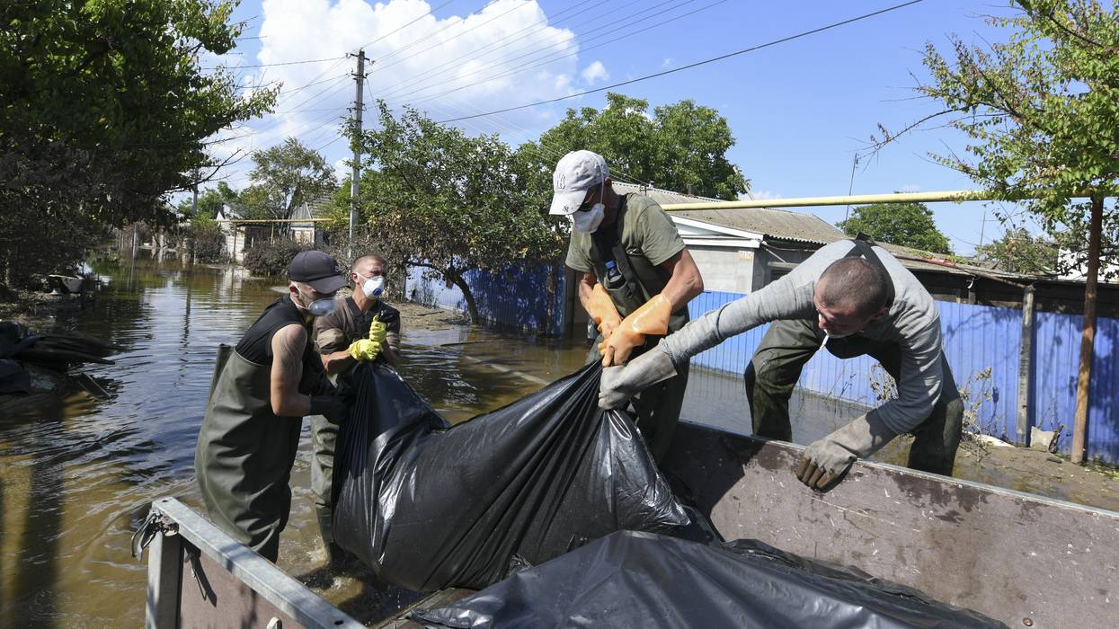 Municipal workers remove dead bodies from flooded houses in Kherson, Ukraine on June 16, 2023, several days after the collapse of the Kakhovka dam.