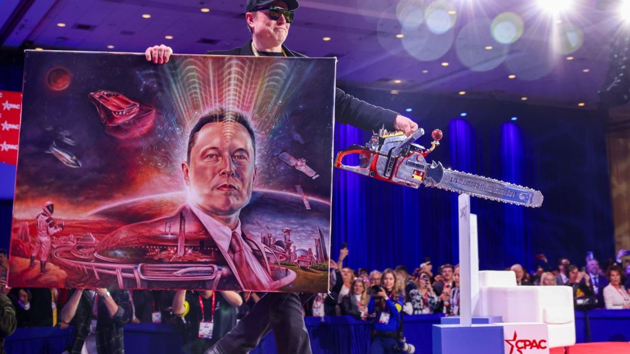 Musk holds a chainsaw and futuristic portrait of himself in space at CPAC 2025