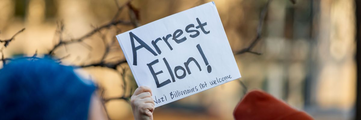 Musk holds up a sign.