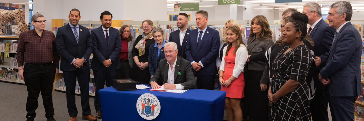 N.J. Gov. Phil Murphy signs the Freedom to Read Act in a library, flanked by educators and advocates
