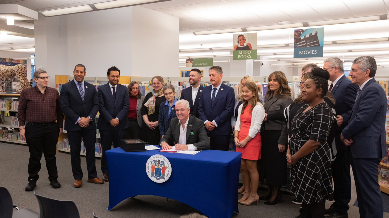 N.J. Gov. Phil Murphy signs the Freedom to Read Act in a library, flanked by educators and advocates