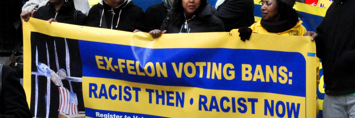 NAACP activists hold a banner reading, "Ex-felon voting bans: racist then, racist now"