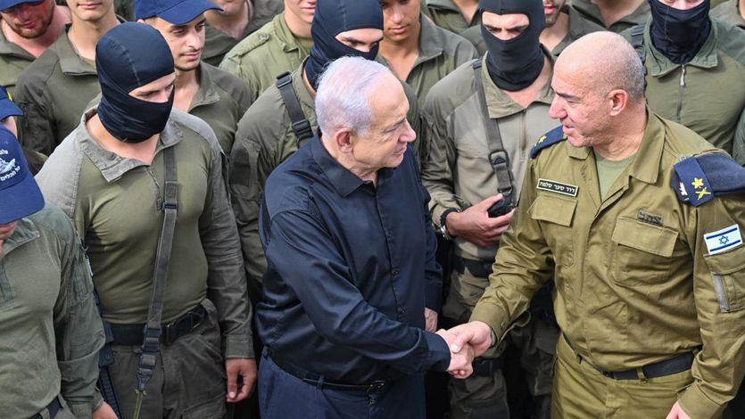 Netanyahu shakes hands with an Israeli naval commander while surrounded by troops in black balaclavas.
