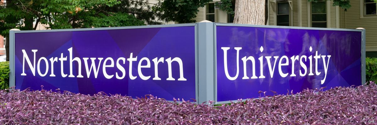 Northwestern University in white letters on a purple sign above purple flowers.