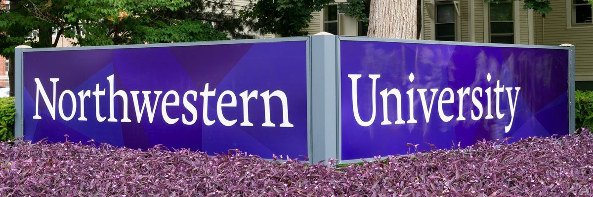 Northwestern University in white letters on a purple sign above purple flowers. 