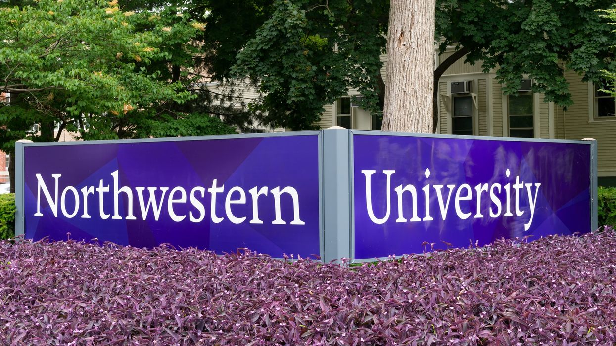 Northwestern University in white letters on a purple sign above purple flowers.