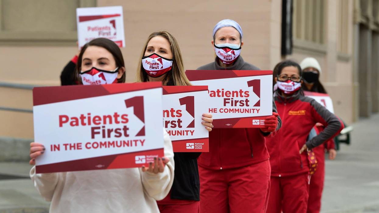 Nurses march carrying signs reading, "Patients first."