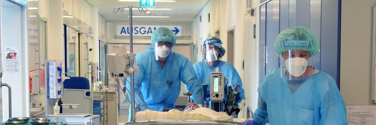 Nurses wheel a patient into a room.