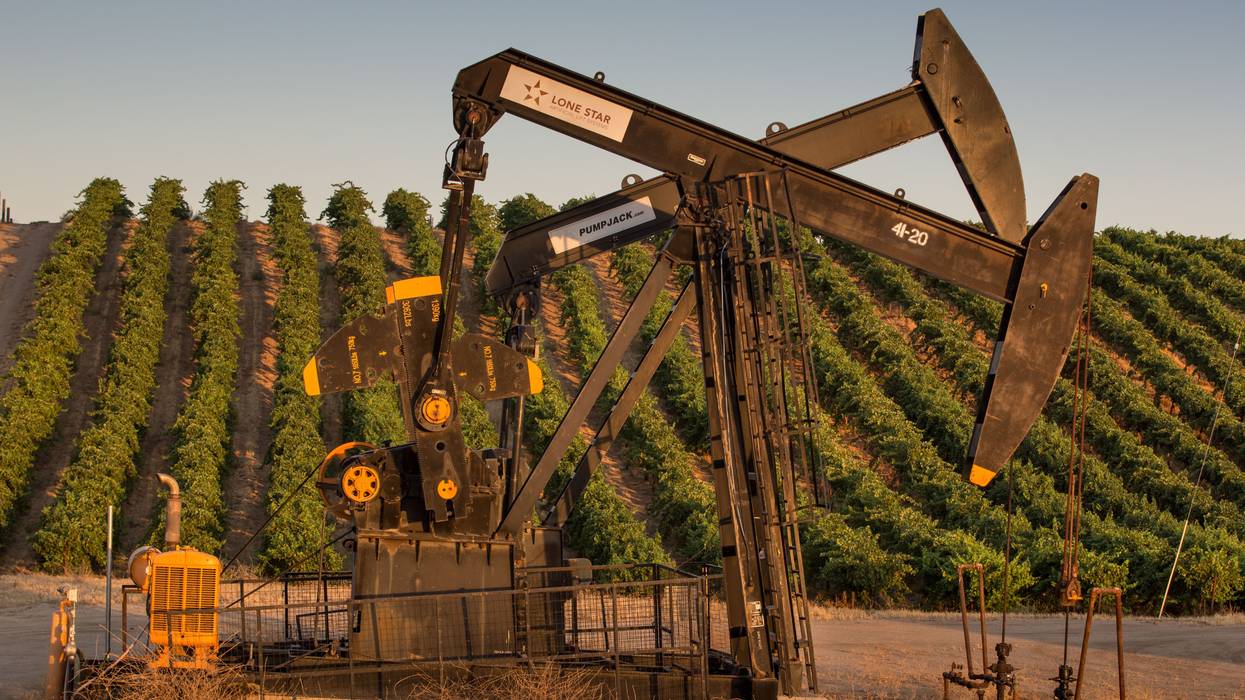 Oil pumping rigs adjacent to a vineyard are seen north of Bakersfield, California on July 8, 2021.