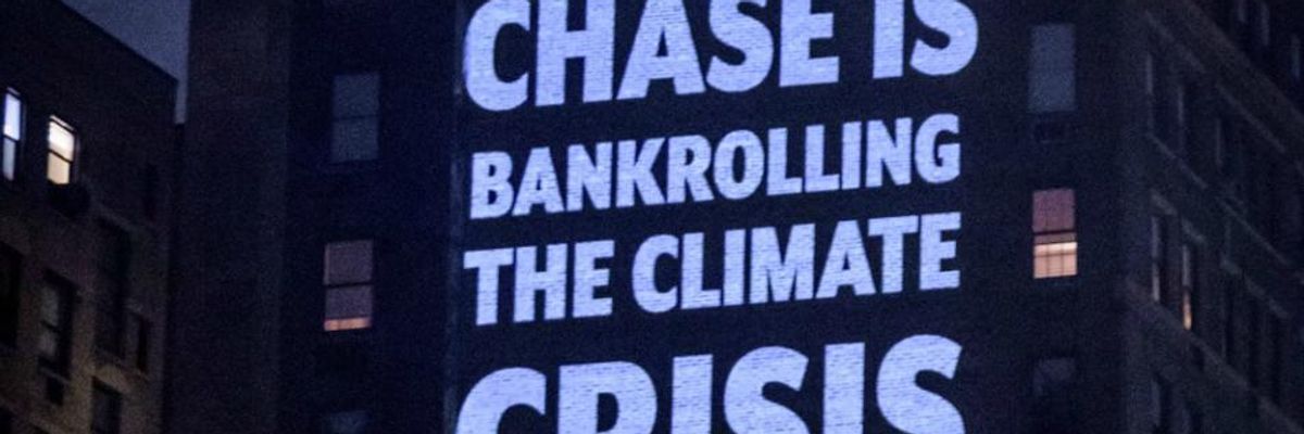 On the night before JPMorgan Chase's annual shareholders meeting, activists with Stop the Money Pipeline projected 30-foot-tall images of people holding protest signs with messages calling on CEO Jamie Dimon to "stop funding fossil fuels" on a wall across from his apartment in New York City