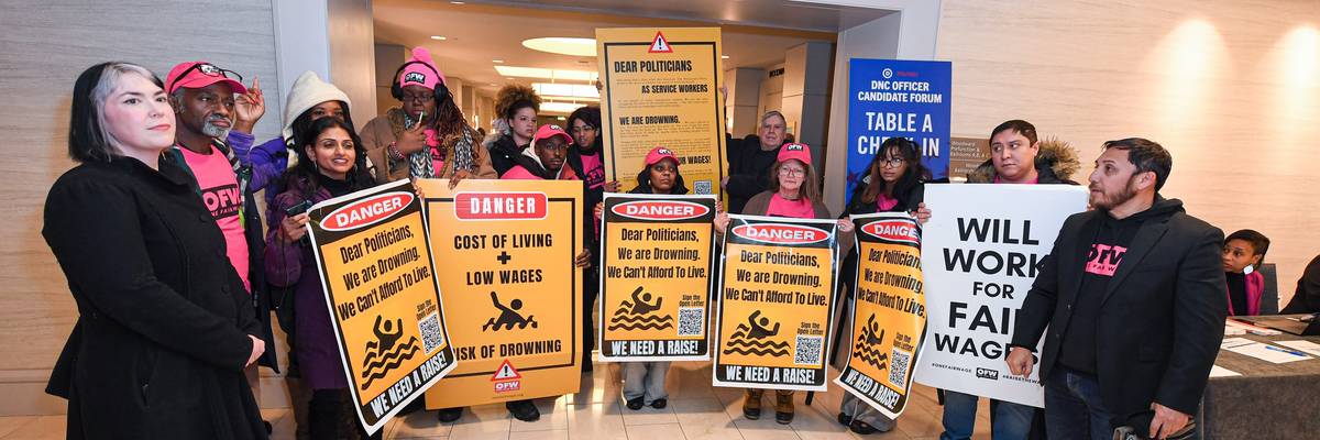 One Fair Wage supporters attend a rally and hold signs advocating for higher wages