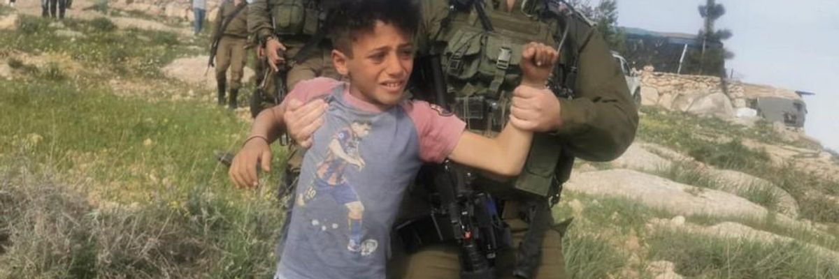Palestinian child being detained by an Israeli soldier
