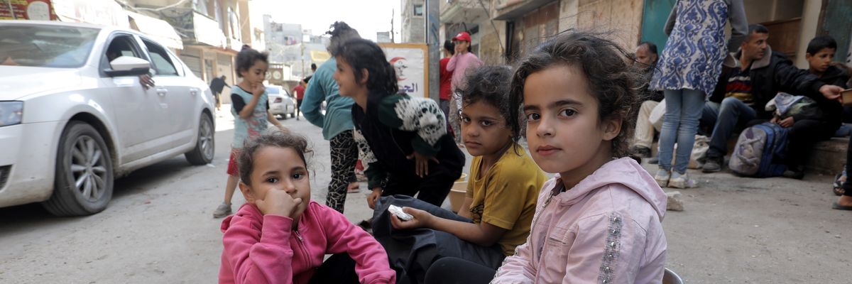Palestinian children in Nuseirat refugee camp wait with empty pots to receive food