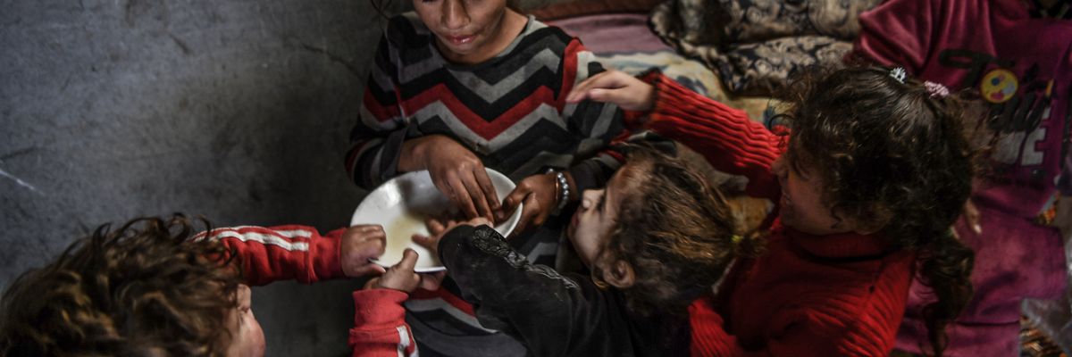 Palestinian children try to eat from a single bowl