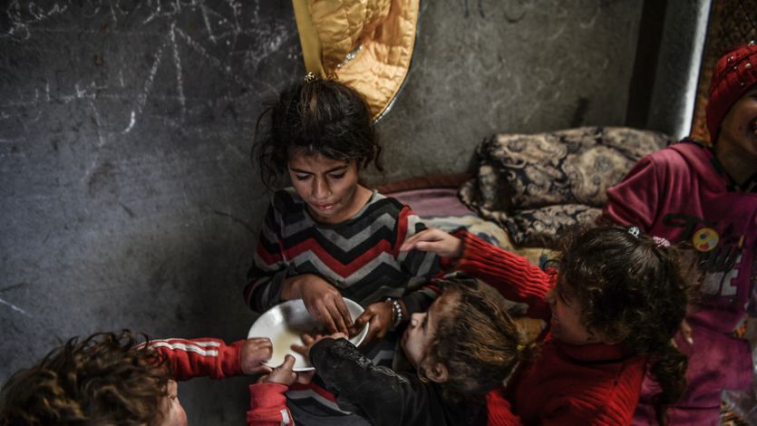 Palestinian children try to eat from a single bowl