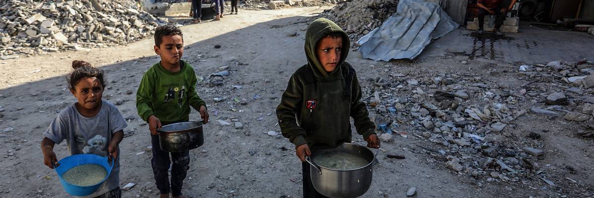 Palestinian children wait in queues for food aid