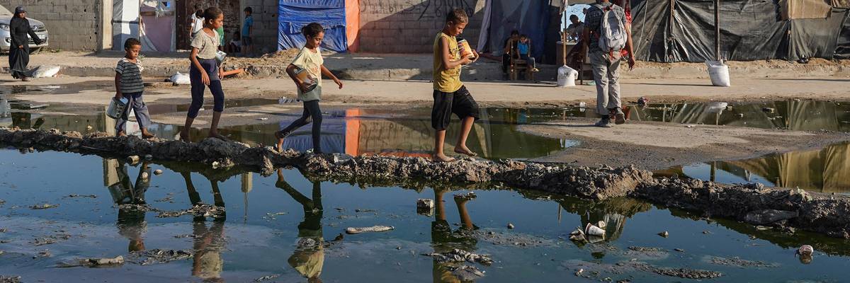 Palestinian children walk near stagnant wastewater