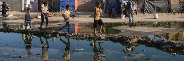 Palestinian children walk near stagnant wastewater