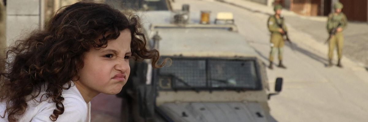 Palestinian girl looking on as Israeli soldiers conduct operation
