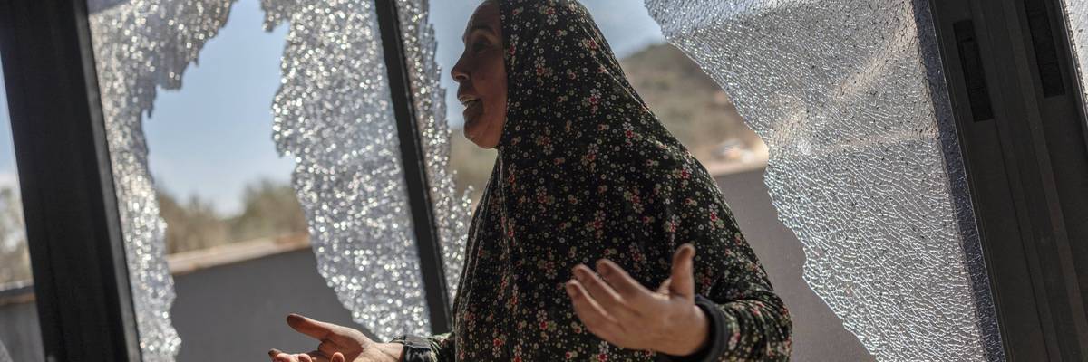 Palestinian Hanan Hamayei gestures as she stands near the shattered glass of her home following a reported attack by Israeli settlers, in the Israeli-occupied West Bank village of Turmus 'Ayya, on October 19, 2026.