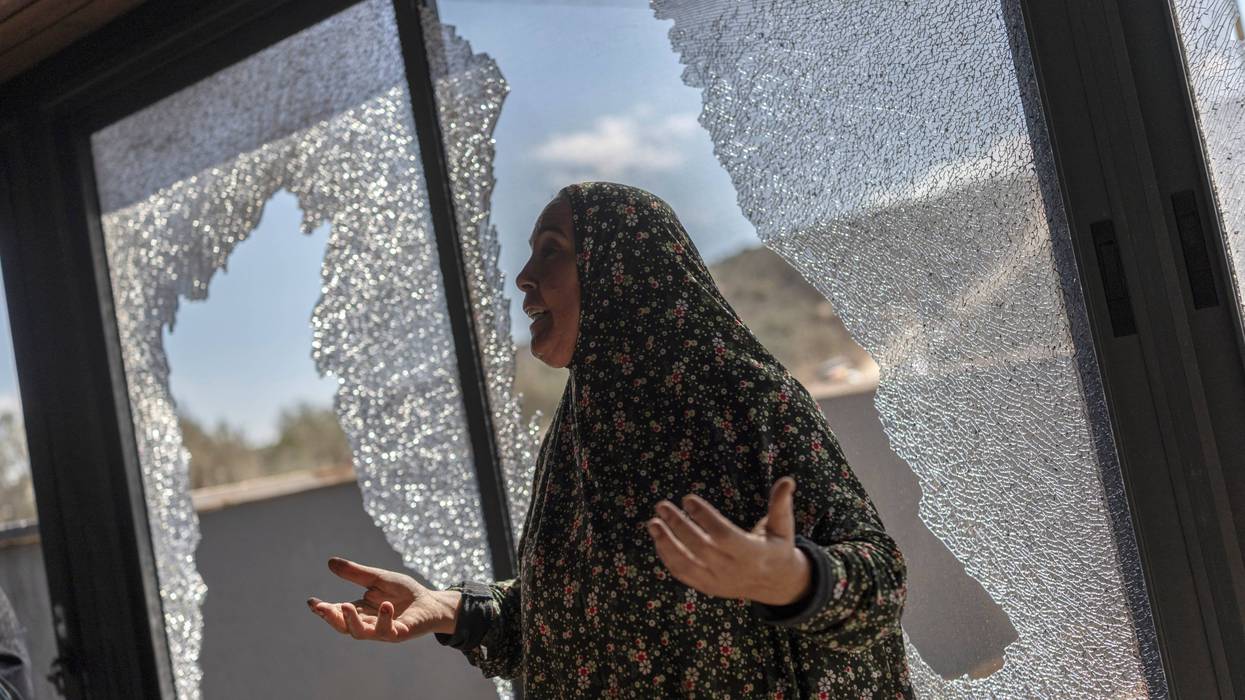 Palestinian Hanan Hamayei gestures as she stands near the shattered glass of her home following a reported attack by Israeli settlers, in the Israeli-occupied West Bank village of Turmus 'Ayya, on October 19, 2026.