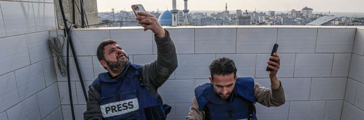 Palestinian journalists attempt to connect to the internet using their phones