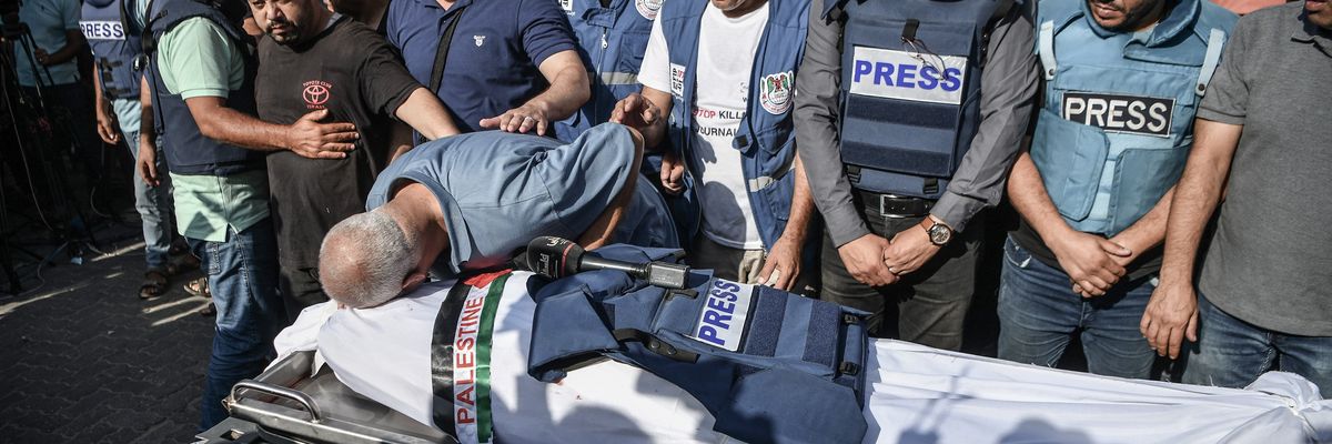 Palestinian journalists in blue "PRESS" flak vests mourn the killing of a colleague by Israeli forces.