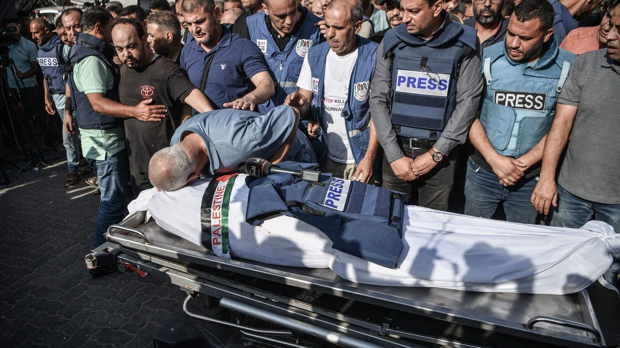 Palestinian journalists in blue "PRESS" flak vests mourn the killing of a colleague by Israeli forces.
