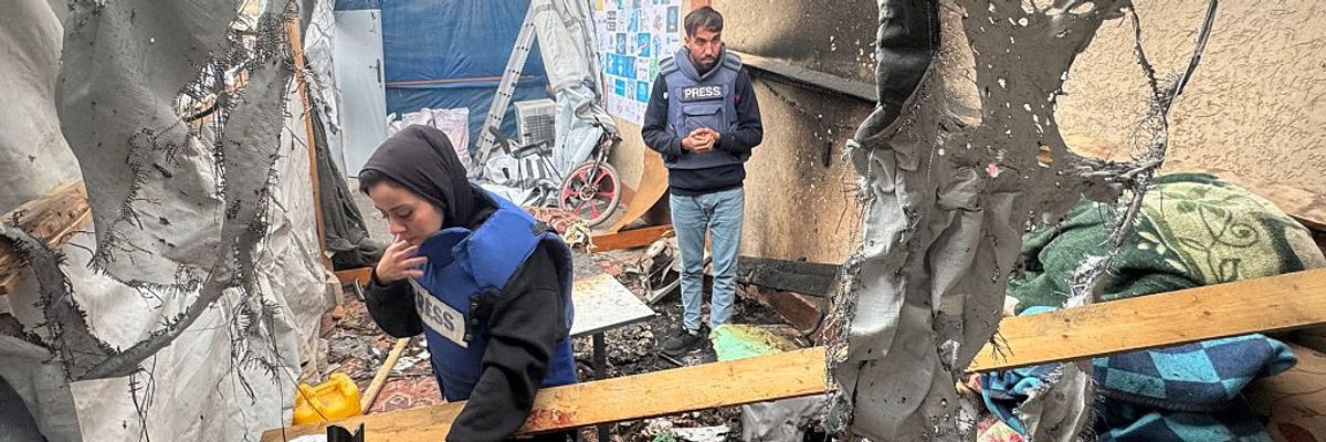 Palestinian journalists inspect what's left of a tent bombed by Israeli forces