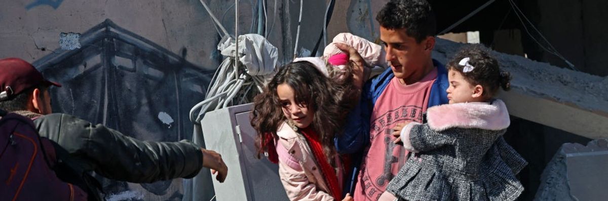 Palestinian man carries two young girls out of rubble following Israeli bombing in Rafah