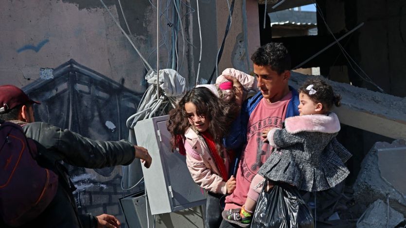 Palestinian man carries two young girls out of rubble following Israeli bombing in Rafah