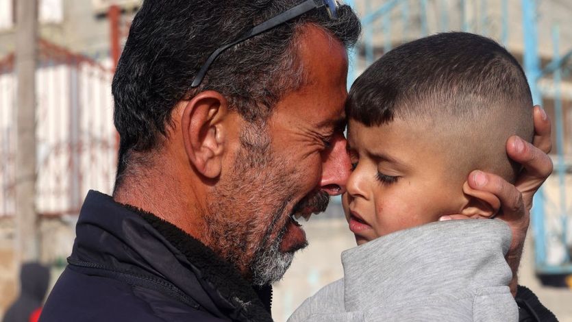 Palestinian man cries as he holds a child