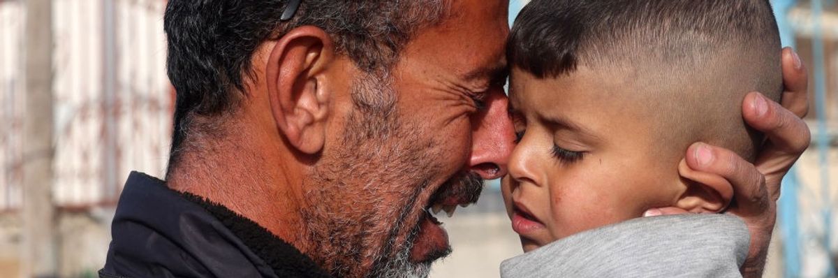 Palestinian man cries as he holds a child