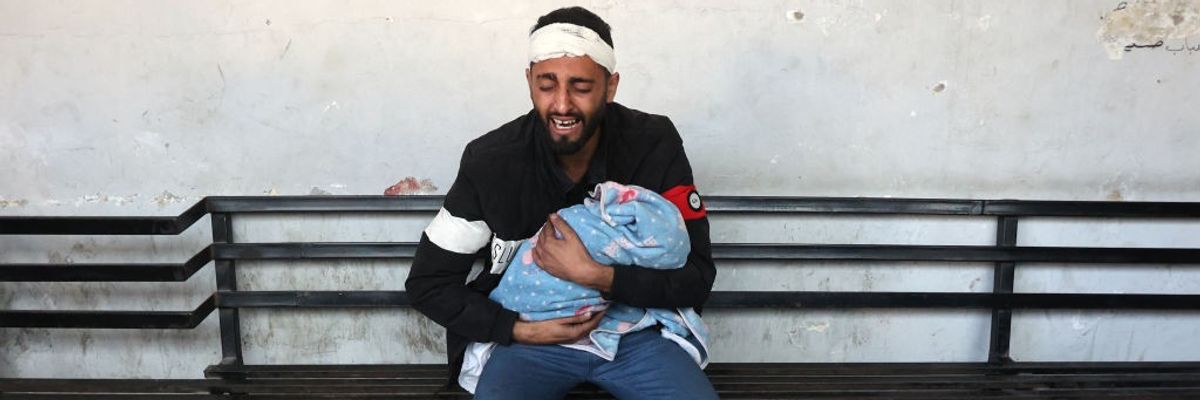 Palestinian man holds dead child killed by Israeli bombing